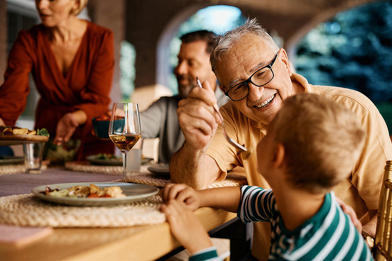 A multigenerational family enjoying a meal together, illustrating the peace of mind provided by comprehensive wealth management for affluent Canadians.